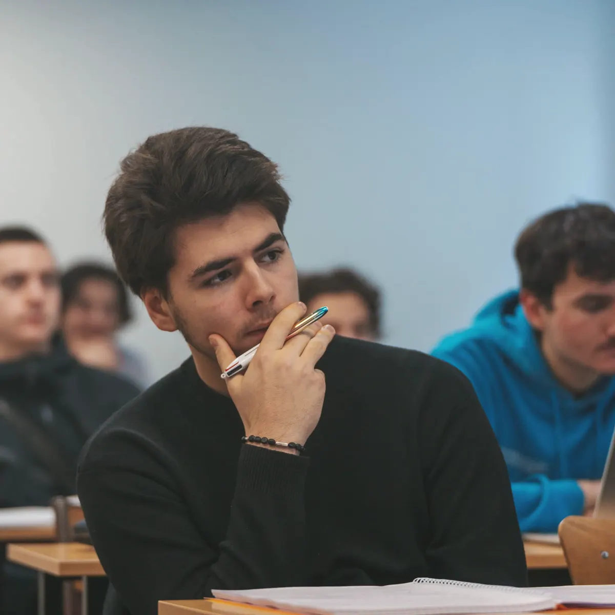 Étudiant en prépa concours Aurlom, stylo à la main, concentré pendant un cours de préparation
